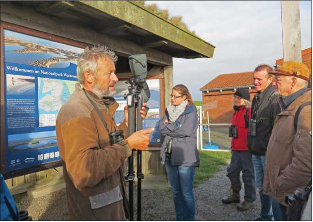 bbildung 5: Dr. Walther Petersen-Andresen erklärt den Exkursions-Teilnehmern im Bel­tringharder Koog ornithofaunistische und ökologische Zusammenhänge am Rande des National­parks „Schleswig-Holsteinisches Wattenmeer“. (Foto: Gisela Martens)